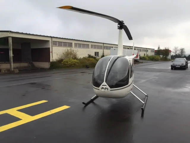 Front view of a Robinson R44 Raven on a helipad with a white paint scheme.