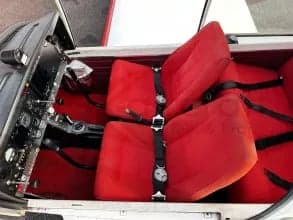 View of the red seats and cockpit inside the aircraft cabin.