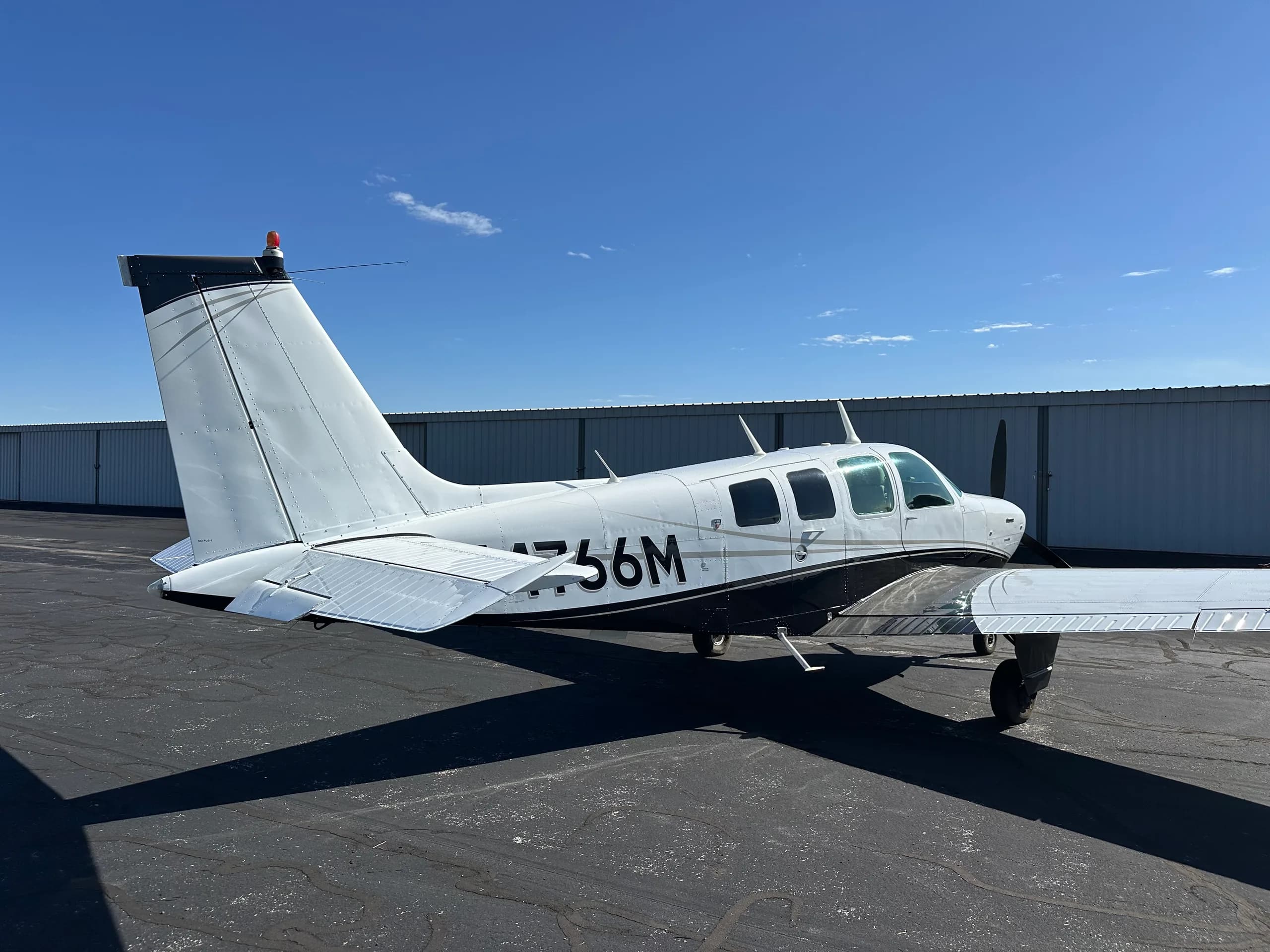 A Beechcraft Bonanza aircraft with registration N4766M is parked on the tarmac.