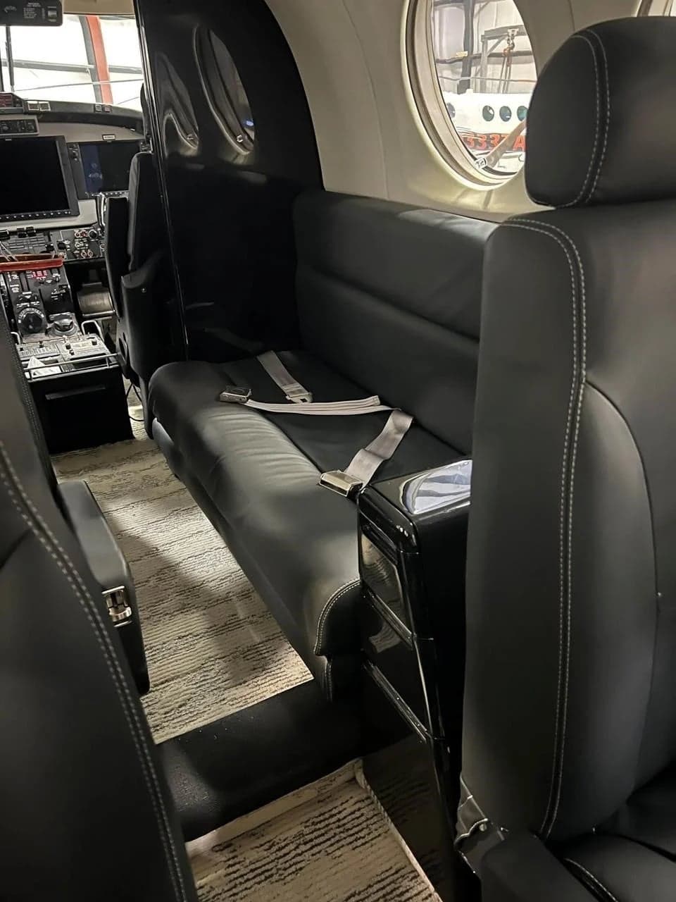 View of the aircraft interior showing the black leather seats and carpeted floor.