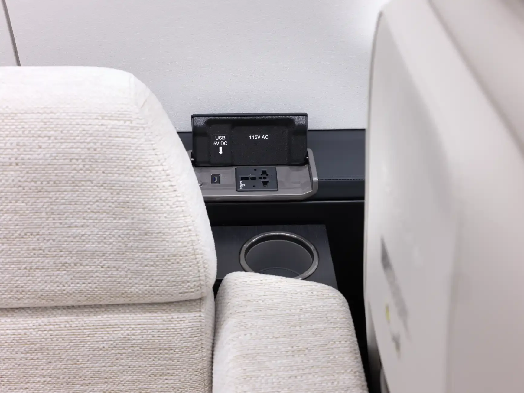 Close-up of the aircraft interior with a power outlet and cup holder.
