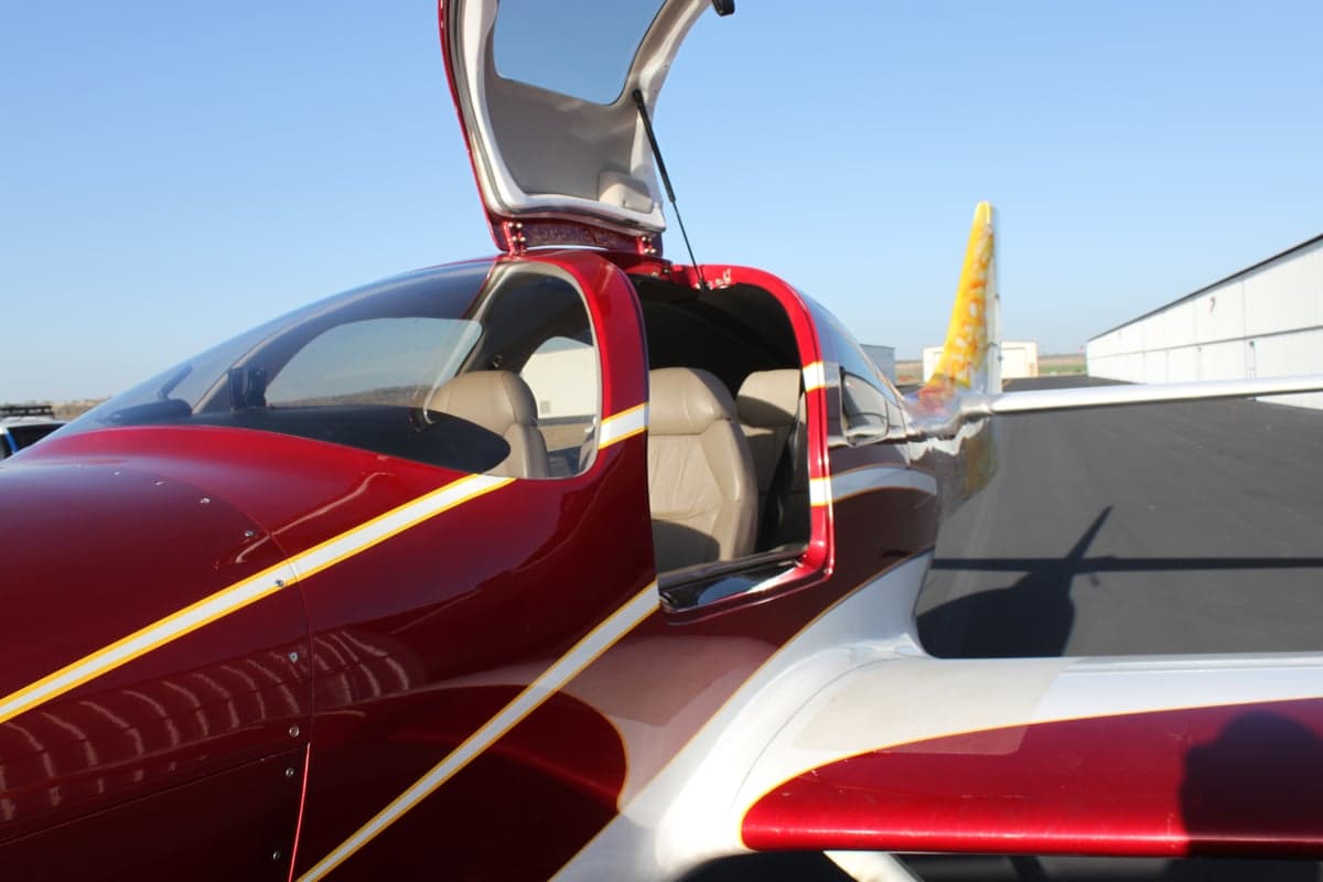 The aircraft's gull-wing door is open, revealing the interior seats.