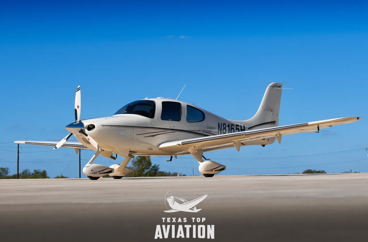 A light-colored Cirrus SR22 is parked on the tarmac.