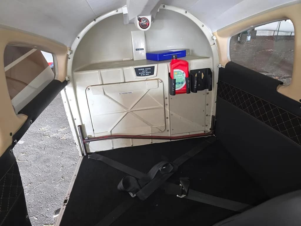 The rear cabin of a small aircraft showing the baggage area with a fire extinguisher and blue box.
