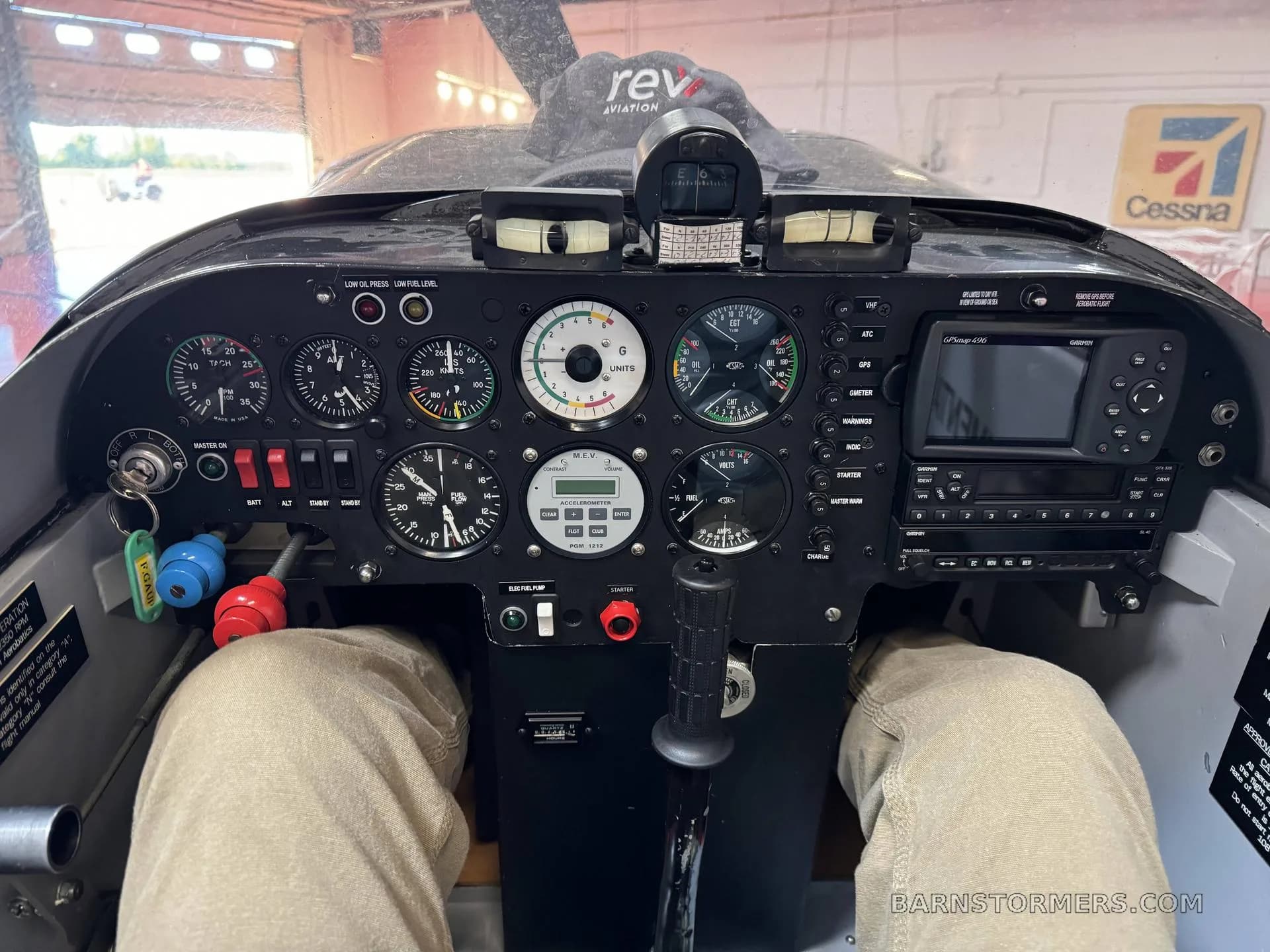 The cockpit of a small aircraft shows the instrument panel with various gauges, switches, and a Garmin GPS unit.