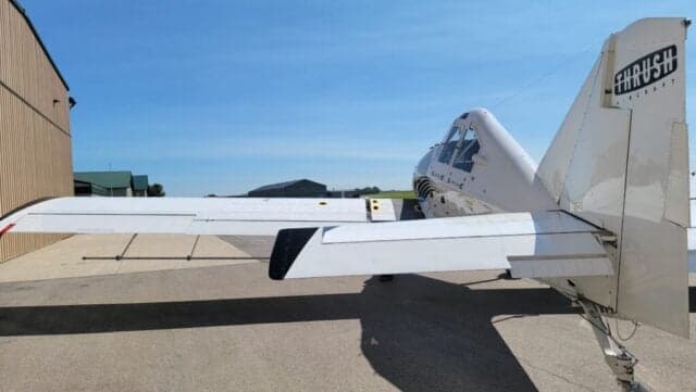 Rear-left view of a white Thrush agricultural aircraft with its full wing span visible.