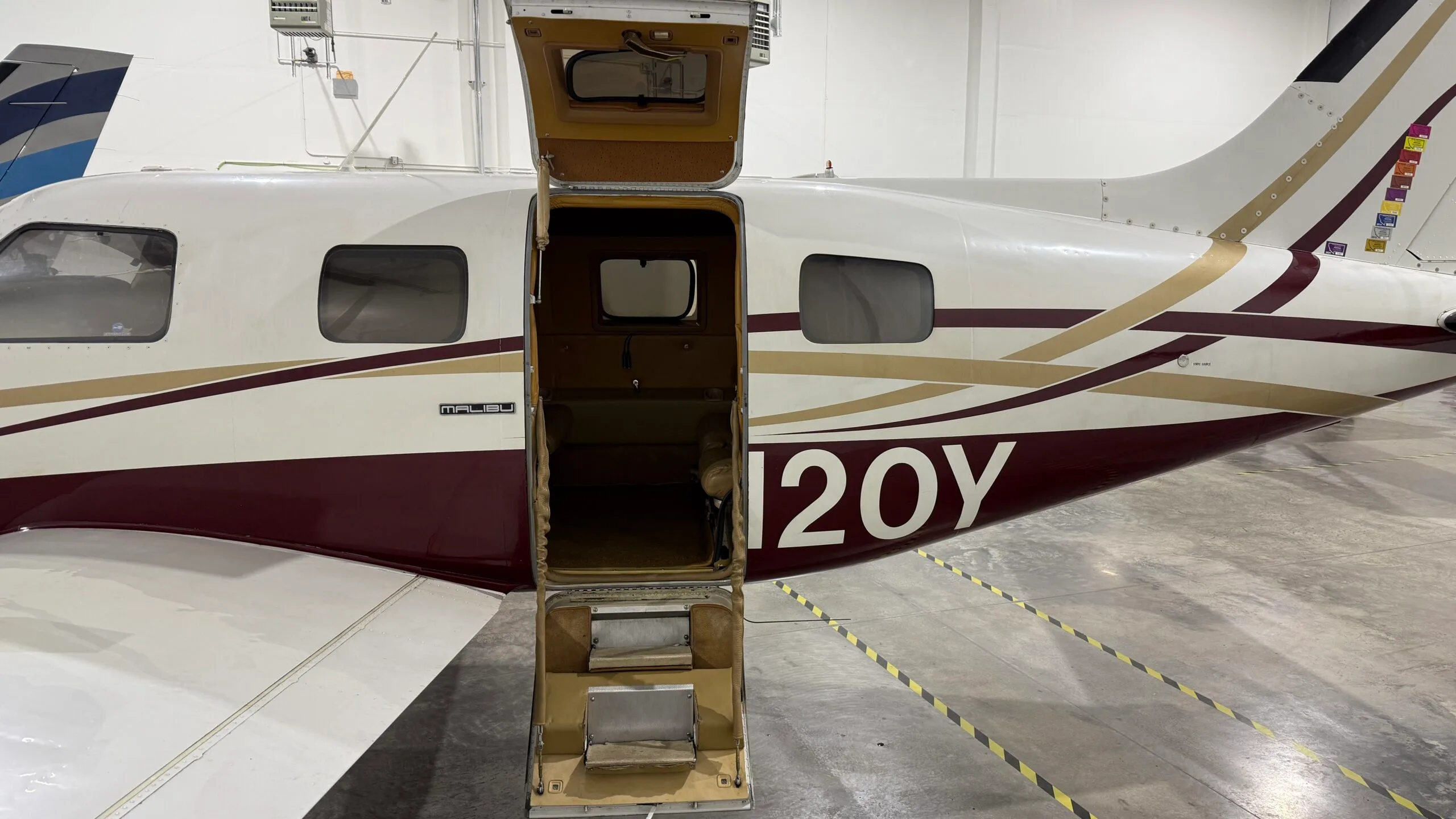 A white and maroon JetPROP aircraft with registration N9120Y with the door open.