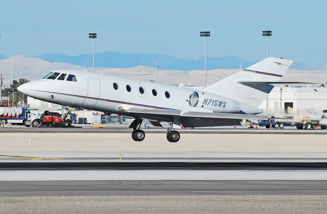 A white Dassault Falcon 900EX aircraft taking off from an airport runway.