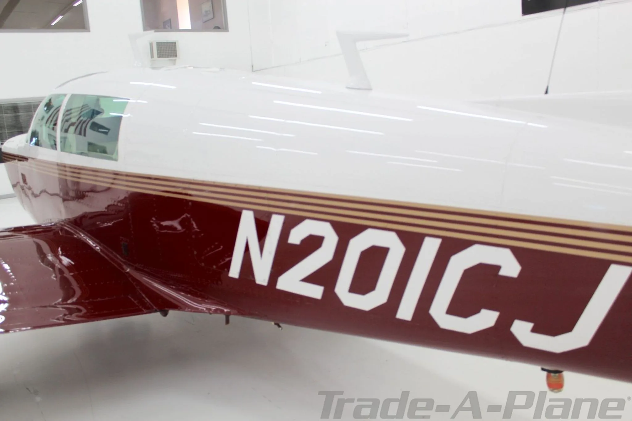 A close-up side view of the Mooney M20J's fuselage, N201CJ, displaying the registration number and paint scheme.