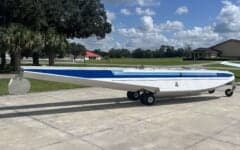 A white and blue aircraft fuselage on a trailer.