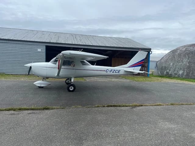 Side view of the C-FZCE Cessna aircraft parked on the tarmac near a hangar.
