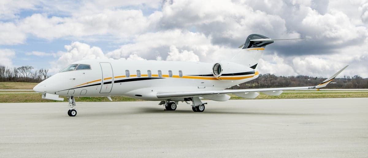 A white and gold Bombardier Challenger parked on the tarmac.