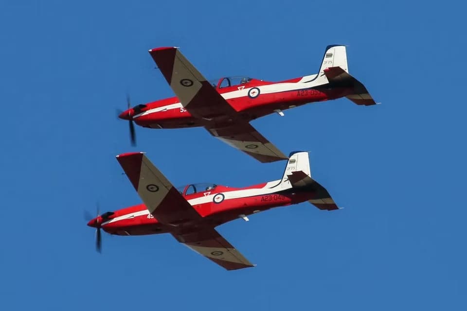 Two A23 aircraft in flight, against a blue sky.