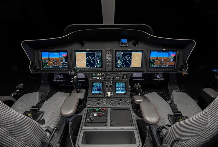 The cockpit of a helicopter with multiple screens and controls.