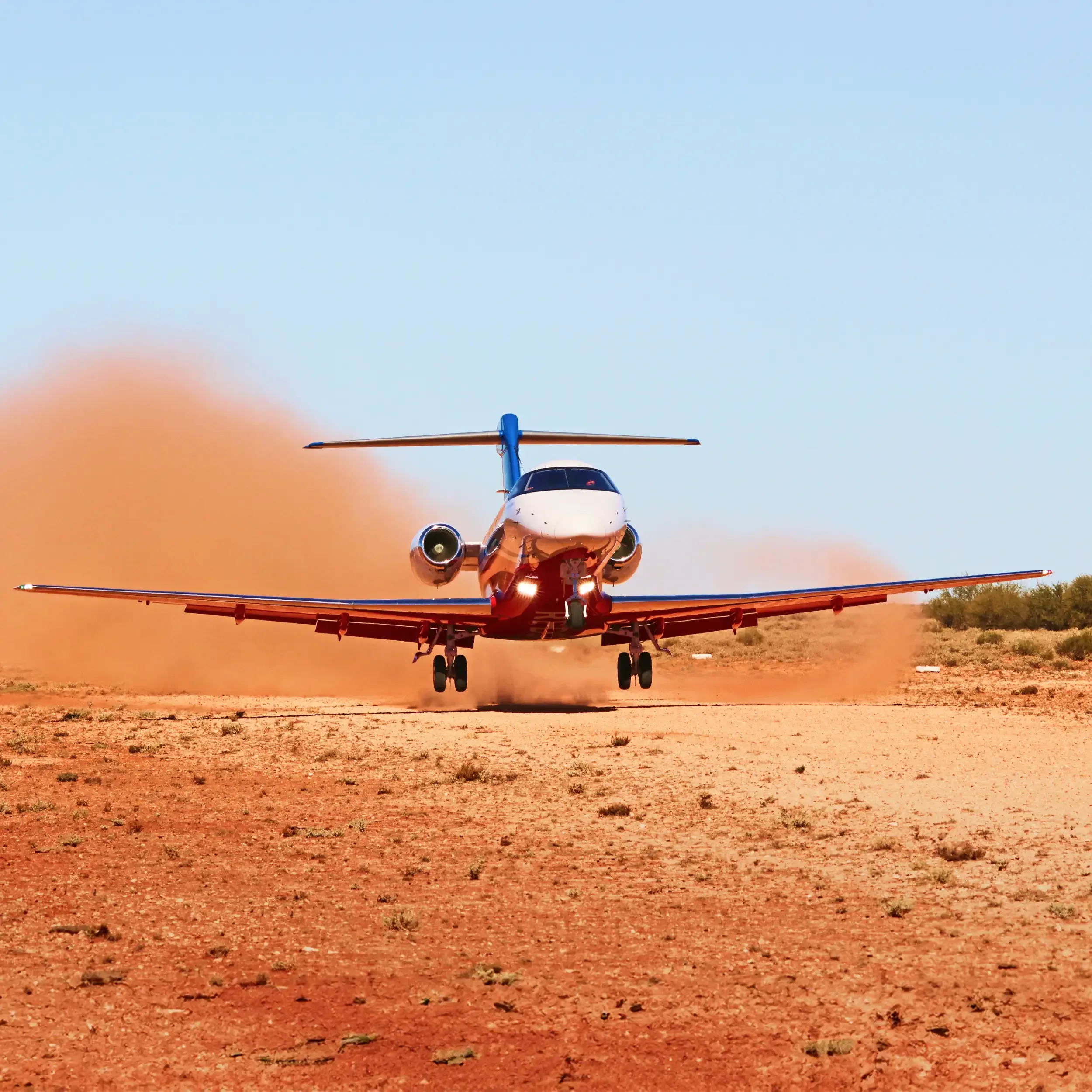 A private jet taking off from a dirt runway, kicking up dust.