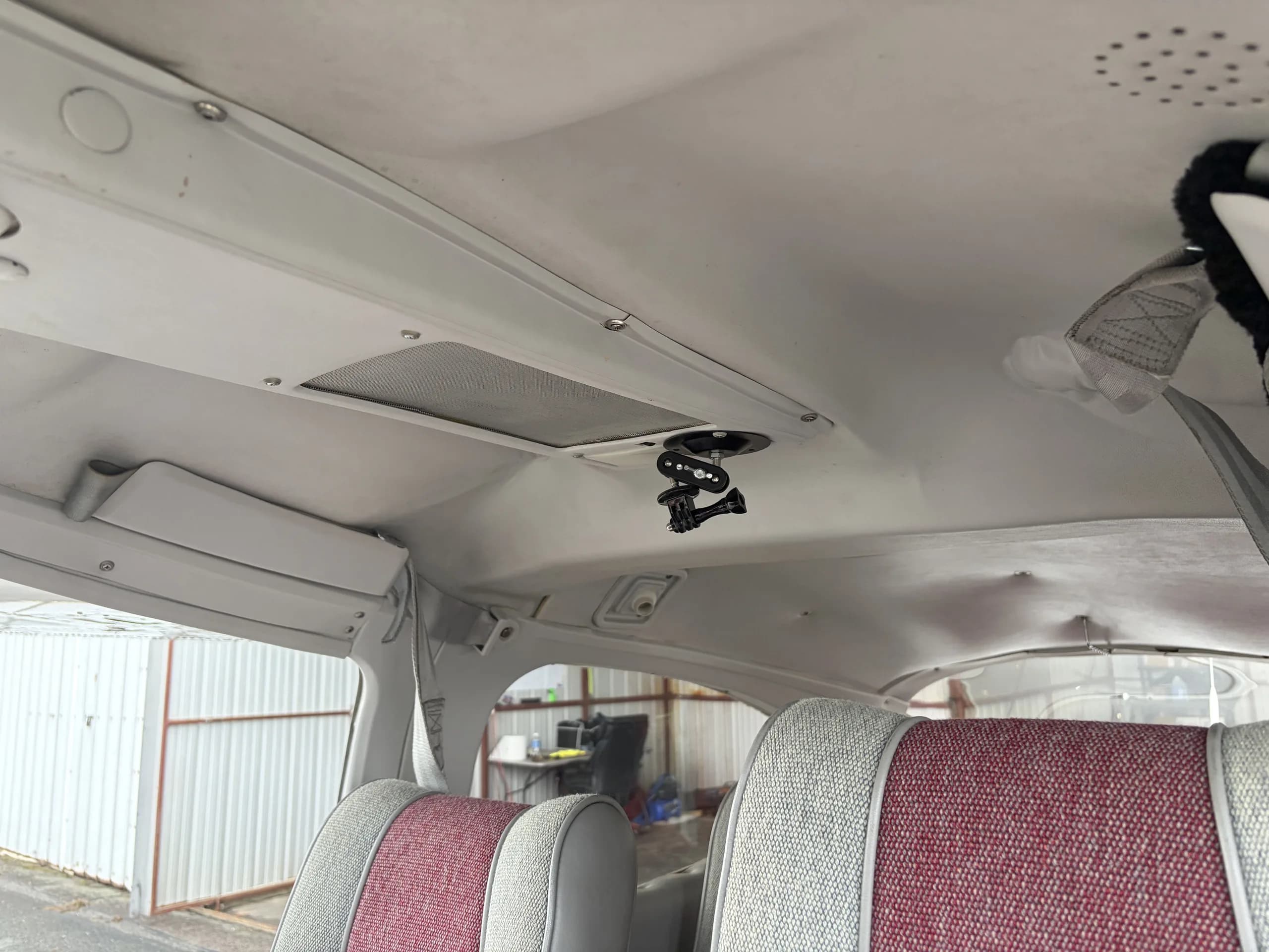 The interior cabin ceiling of the aircraft, showing overhead vents and a camera mount.