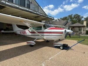 A Cessna 182 Skylane, registration N71699, parked under a covered area with a tow bar attached.