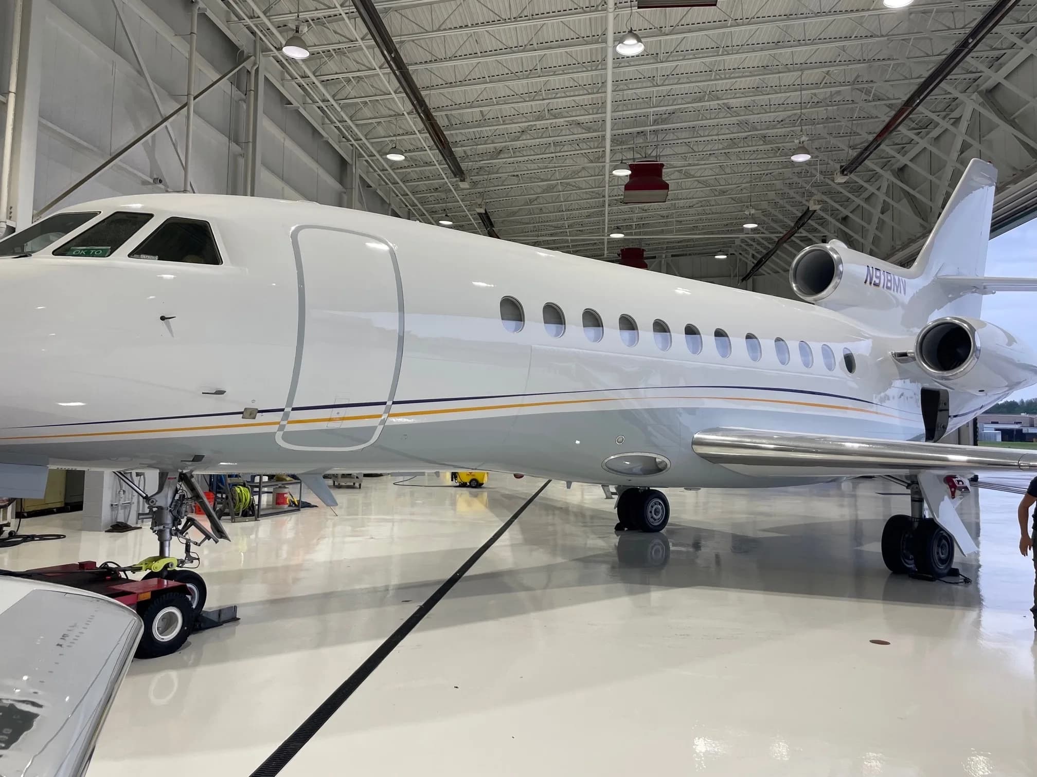 A Falcon aircraft with registration N918MV is parked inside a hangar.