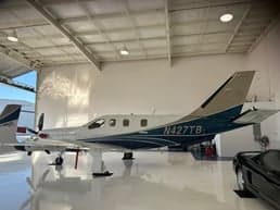 A TBM 930 aircraft is parked inside a hangar, showcasing its white and blue paint scheme.