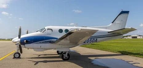 Side view of a white and blue King Air aircraft on the tarmac.