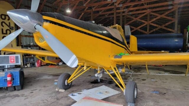 A yellow and black Air Tractor AT-400 sits inside a hangar.