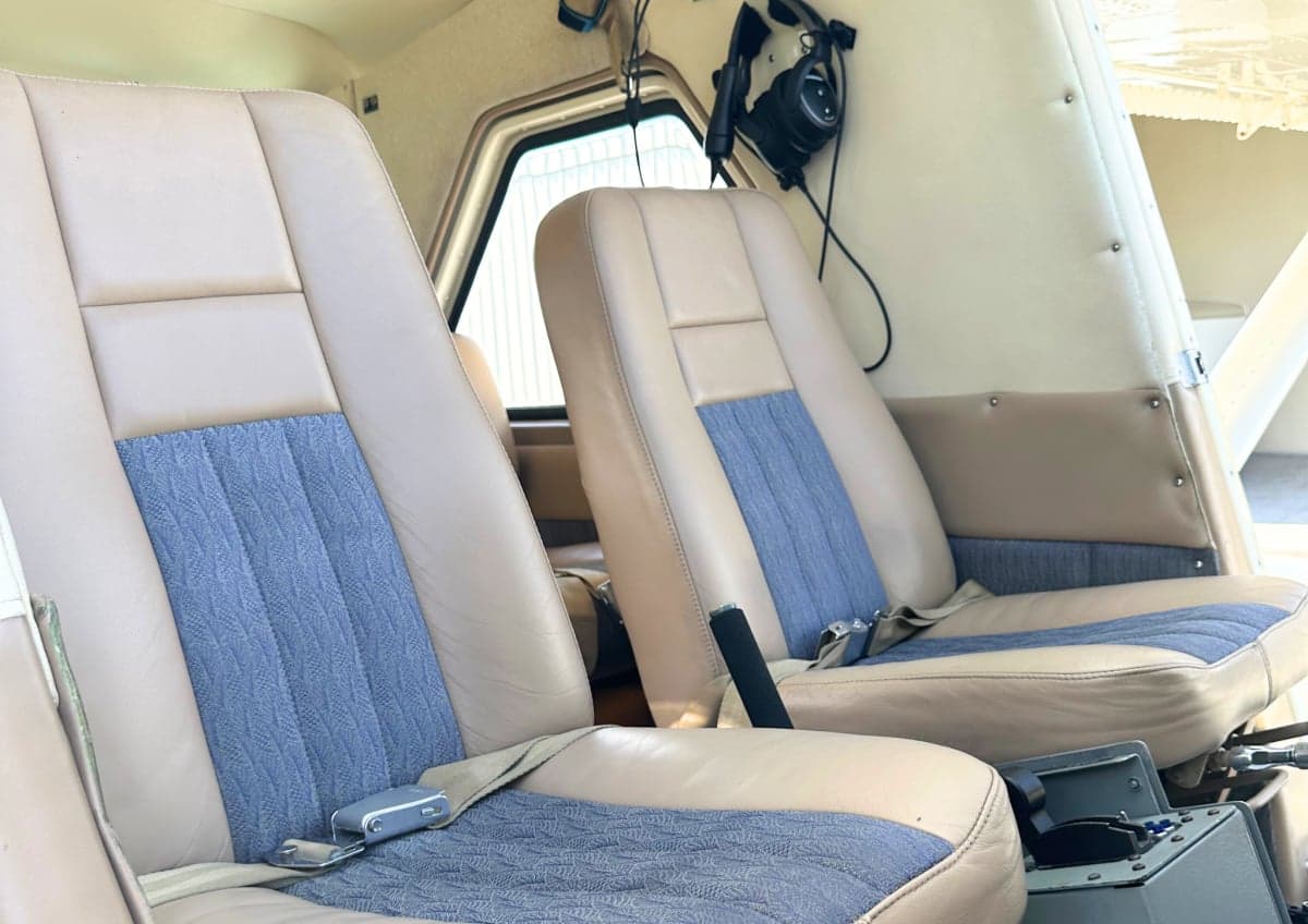 The aircraft's interior features tan leather seats with blue fabric inserts.