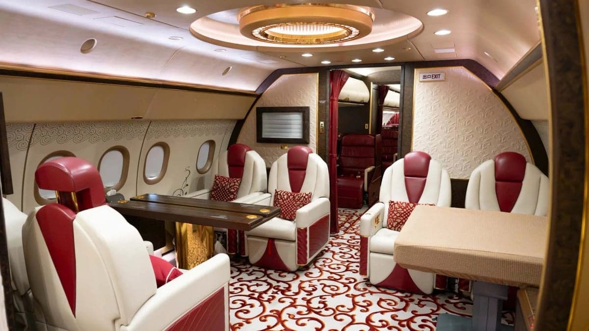 The interior of a private jet with white and red leather seats and a table.
