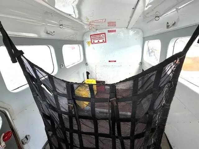 The interior cabin of an aircraft showing a large black cargo net hanging from the ceiling.