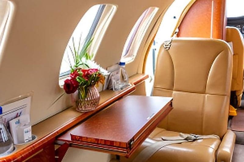 Close-up of an aircraft seat with a table and flowers.