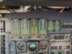 A blurry view of the Challenger aircraft cabin with beige leather seats and monitors.