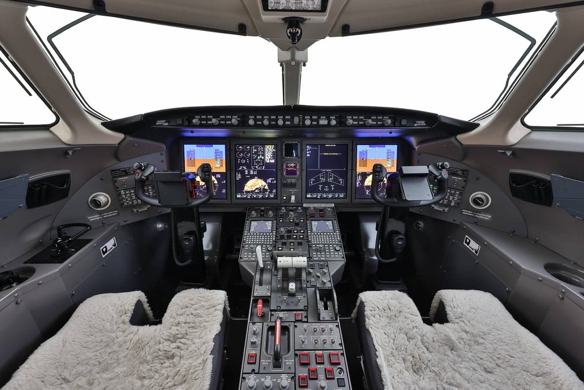 View of the aircraft's cockpit with multiple screens and controls.