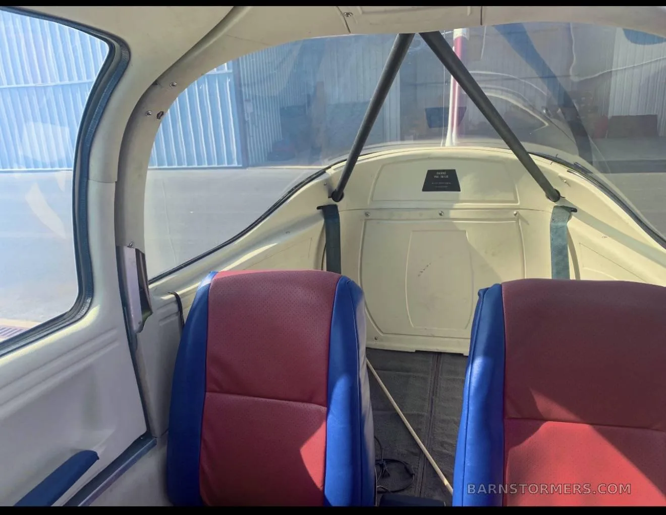 The interior of an aircraft cabin with red and blue seats and a view towards the rear.
