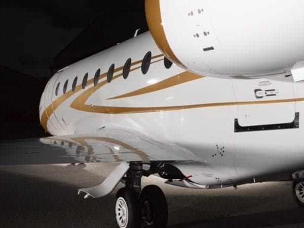 Close-up of the side of a white and gold aircraft, showing the wing and landing gear.
