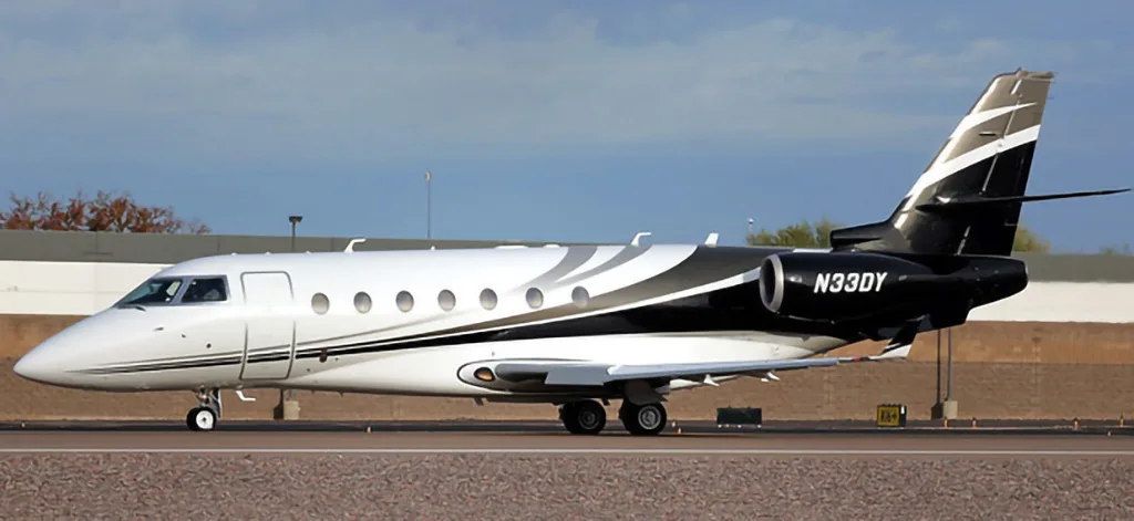 A white and black business jet with registration N33DY is seen from the side on a tarmac.