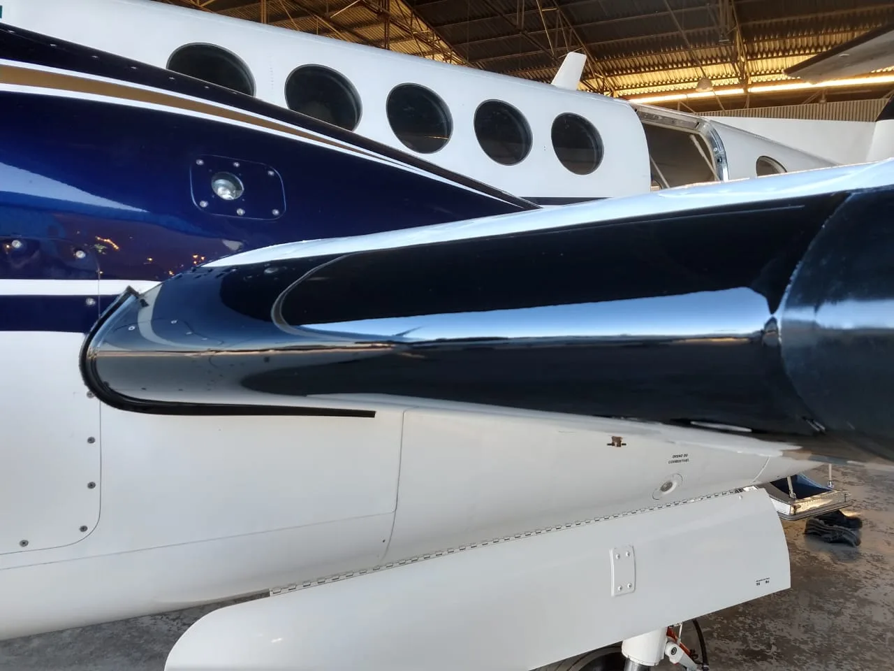 Close up of the wing and fuselage of a Beechcraft King Air 200 inside a hangar.