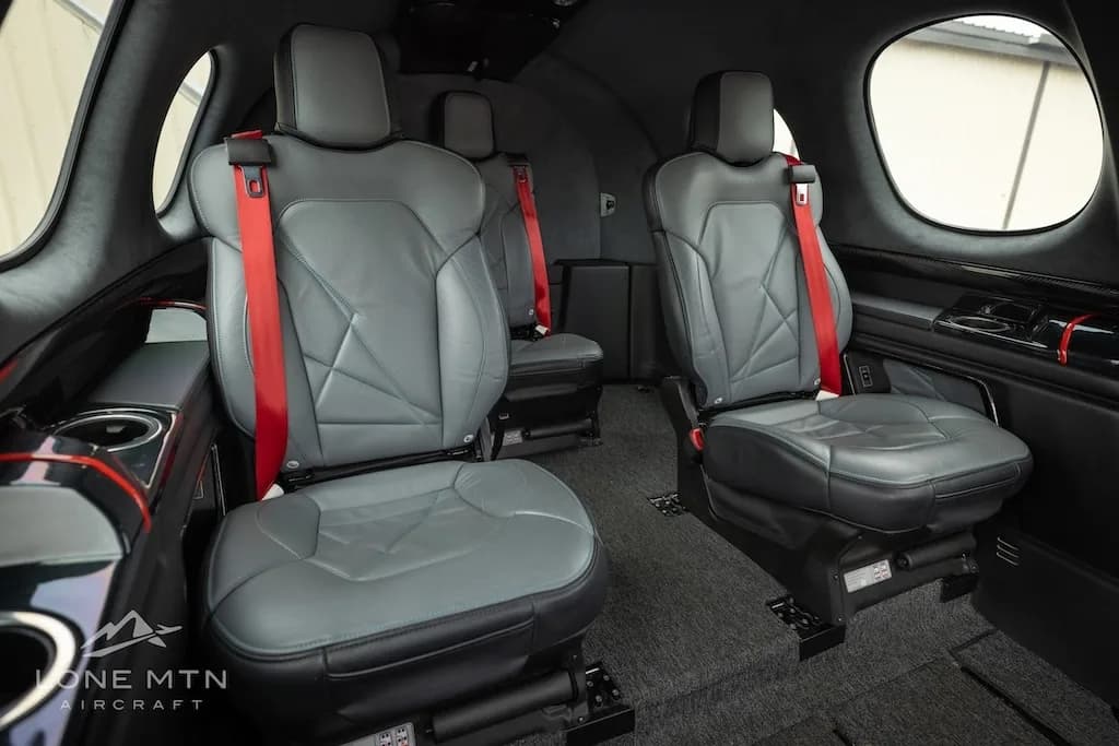 The interior cabin of the Cirrus Vision Jet showing grey seats with red seatbelts.
