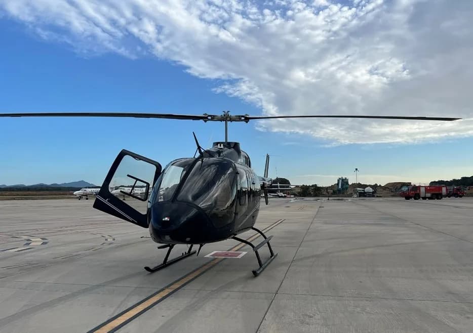 Front view of a black helicopter with open doors on the tarmac.
