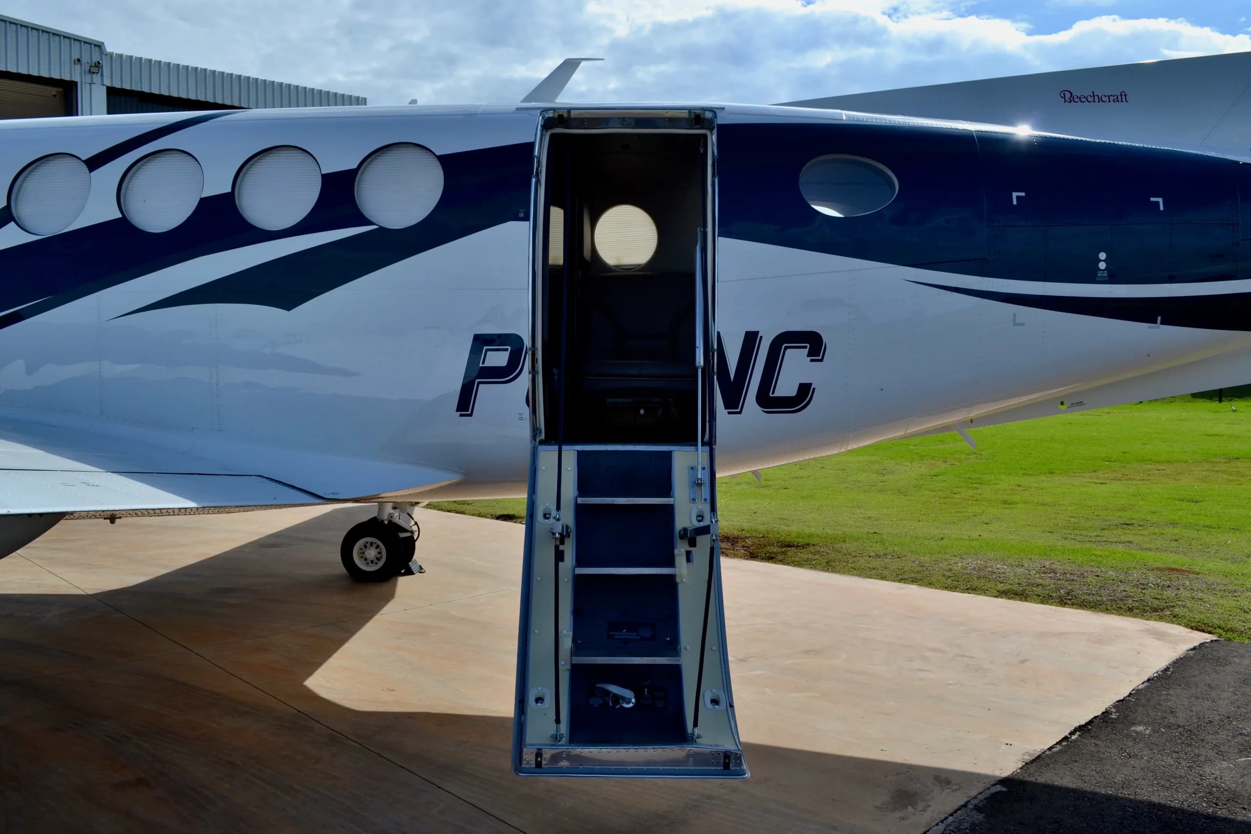 A close-up view of the open passenger door and extended stairs of a white and blue aircraft.