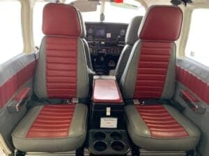Front seats of the aircraft cabin with red and gray upholstery.