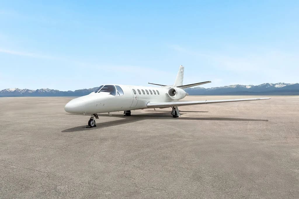 A white Cessna Citation CJ3 (N102VP) parked on a tarmac with mountains in the background under a clear sky.