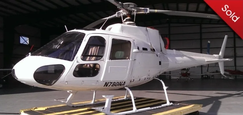 A white helicopter with registration N780NA is parked inside a hangar, viewed from the front-right.