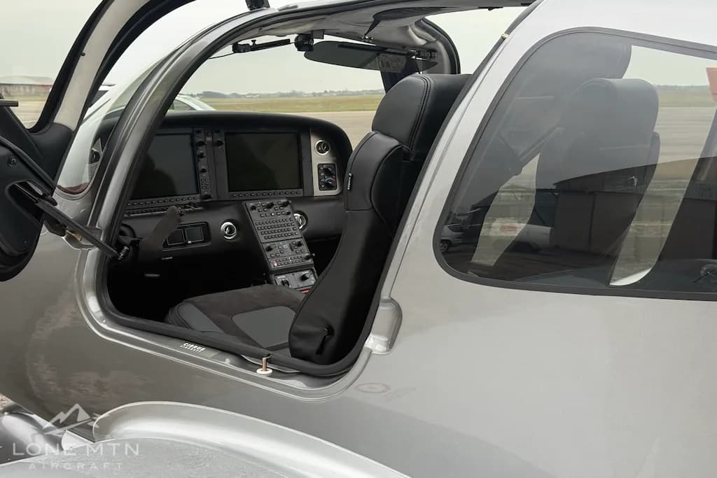 The interior of the Cirrus SR22, showing a black pilot's seat and part of the glass cockpit through an open door.
