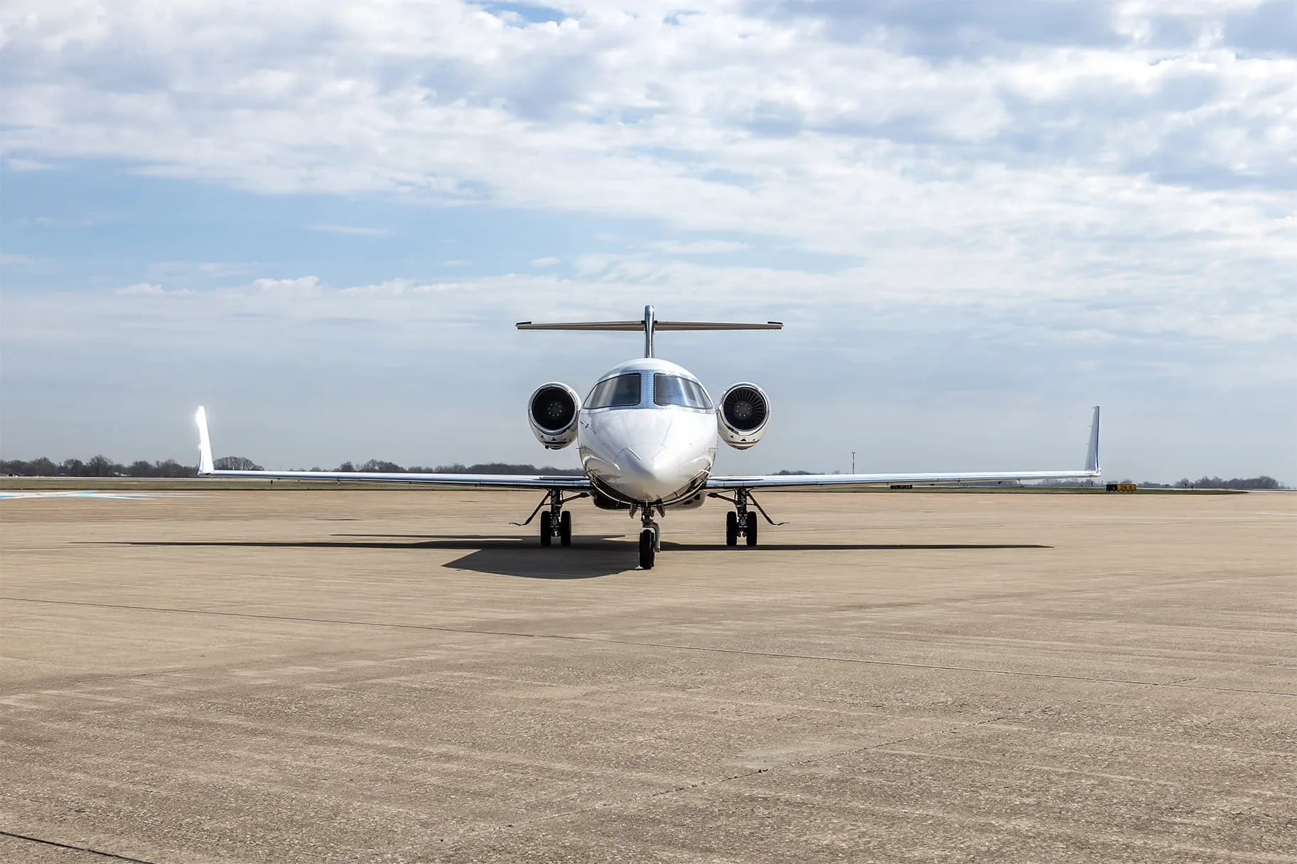 A head-on view of a Learjet 60 business jet with a white and black paint scheme parked on an airfield.