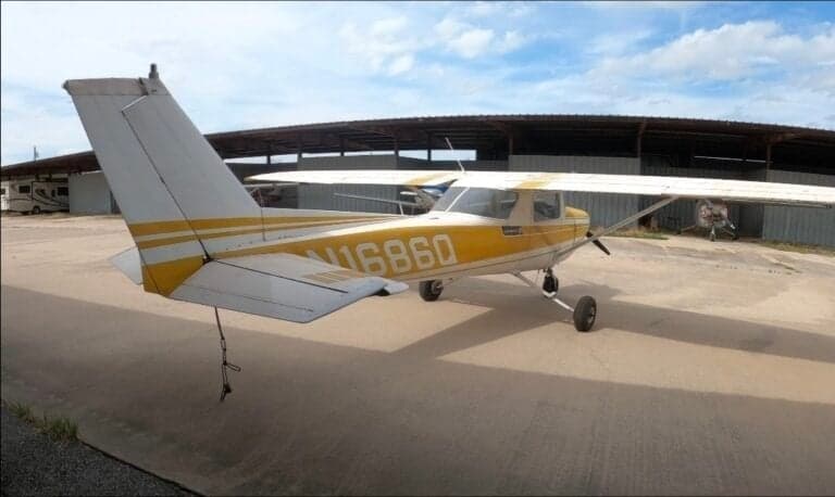 Rear view of a yellow and white Cessna 150 with tail number N1686Q parked on the tarmac.