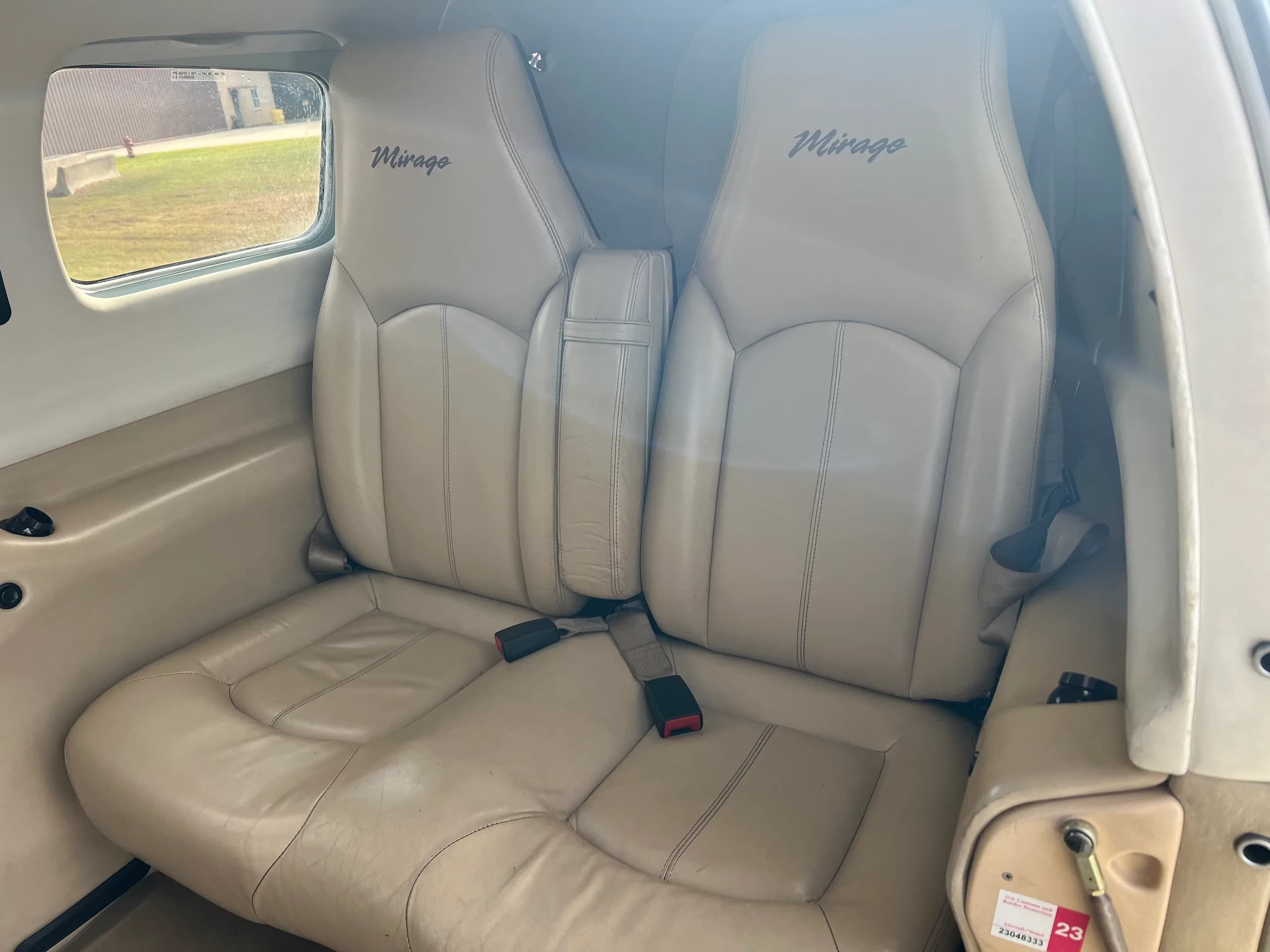 Two beige leather passenger seats with "Mirage" embroidered, in the cabin of the aircraft.