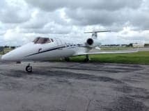 Front side view of a white Learjet on the tarmac.