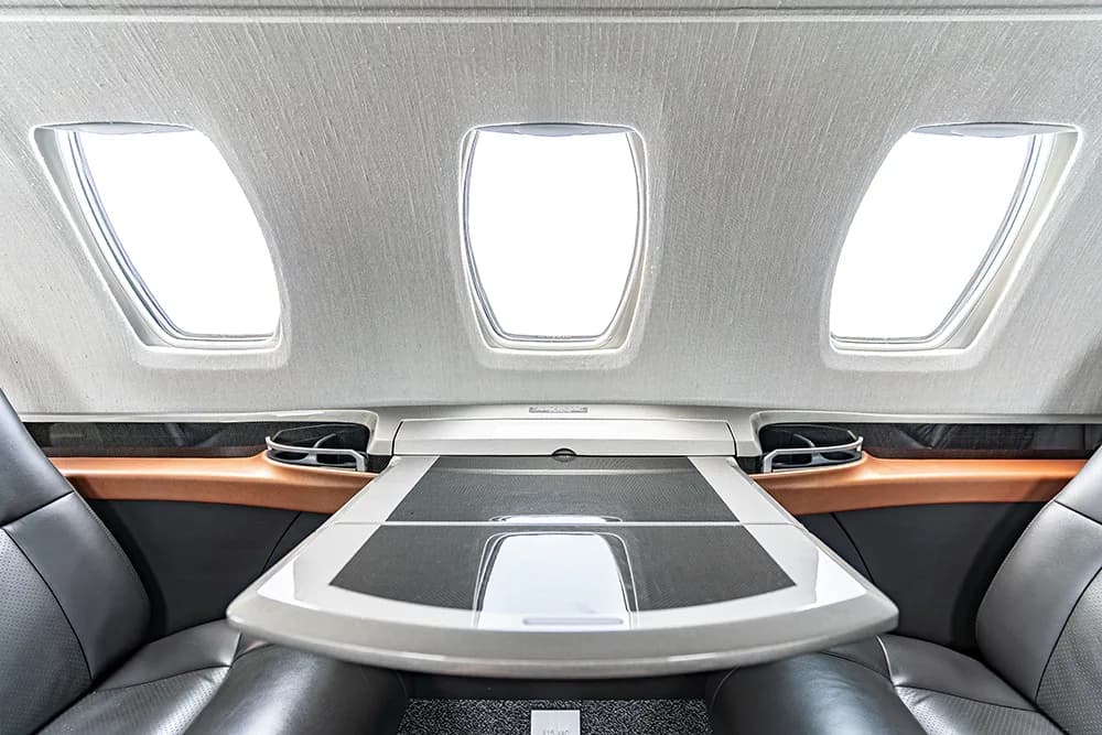The rear section of the aircraft cabin interior with a large table and three windows.