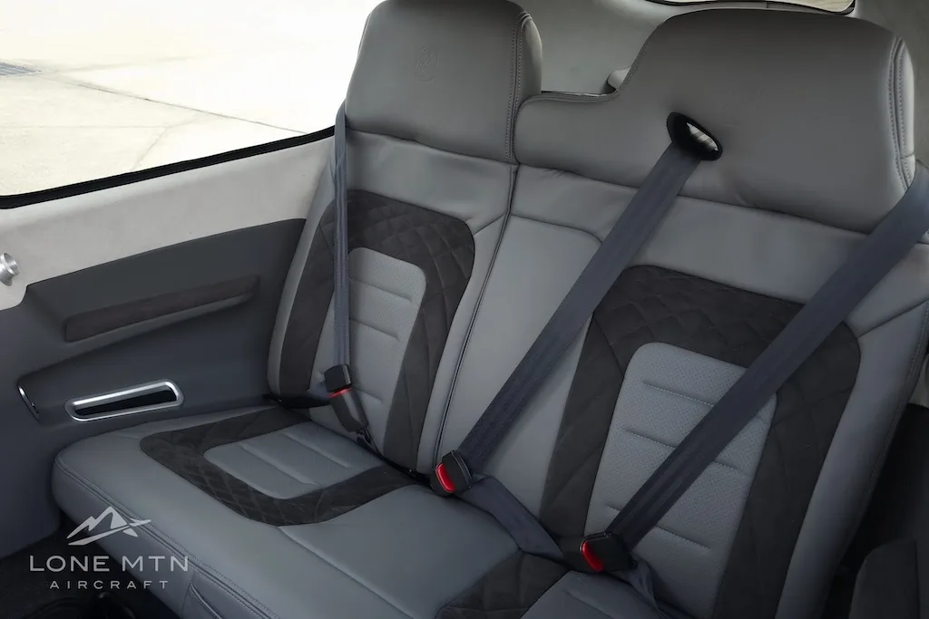 The gray leather rear seats of a Cirrus SR22 aircraft cabin with seatbelts visible.