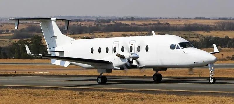A front side view of a white King Air aircraft on the runway.