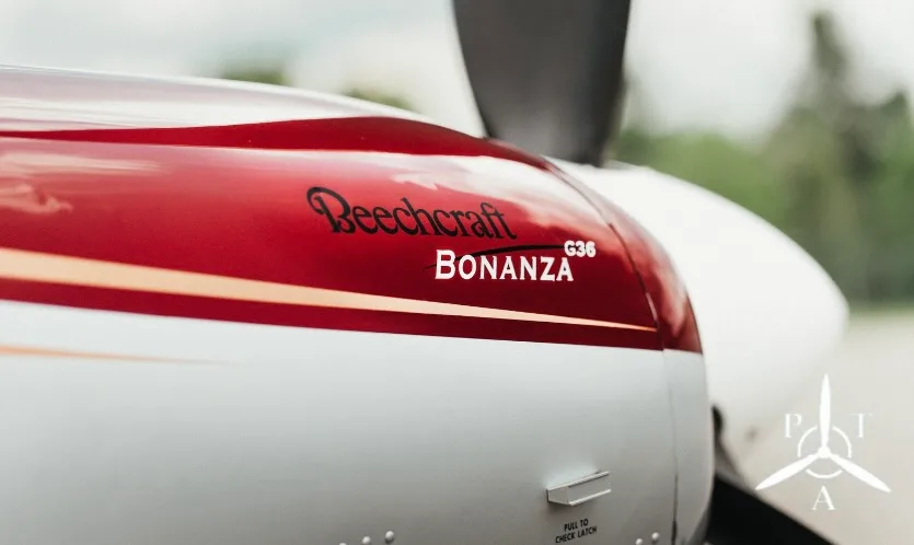A close-up view of the red and white cowling of a Beechcraft Bonanza S35 aircraft.